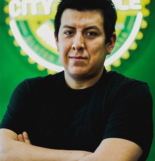 Portrait of City Tamale founder Isrrael Veliz in front of the restaurant logo